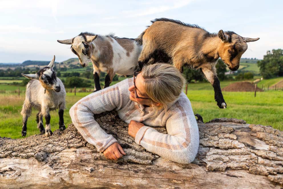 A woman and her three pygmy goats on a farm.